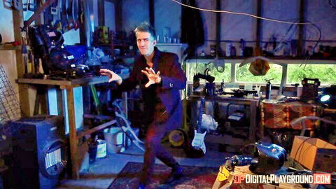 Dramatic man in black suit striking intense pose in garage workshop with tools and amps