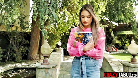 Sexy brunette teen babe in pink sweater and jeans posing outdoors in garden