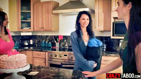 Three sexy brunettes in kitchen smiling over pink birthday cake teasing seduction