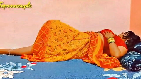 Curvy Indian babe in orange saree lying seductively on bed, big boobs