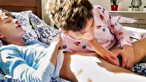 Young gay guys in pink and blue PJs passionately neck kissing and thigh groping on bed