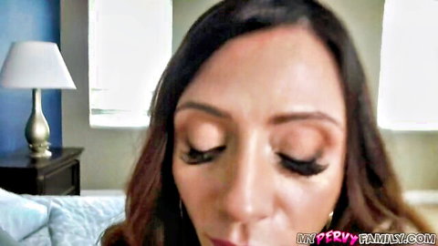 Seductive brunette MILF with heavy lashes stares intensely at POV camera in bedroom