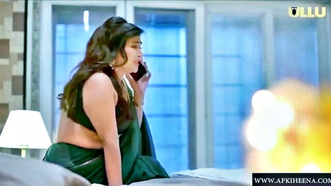 Curvy Indian woman in revealing backless green saree talks on phone sitting on bed
