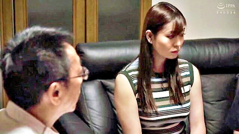 Japanese MILF housewife in striped tank top sits intimately with older man on black leather couch