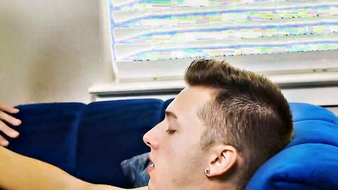 Handsome twink lying back on blue couch eyes closed mouth open in handjob pleasure