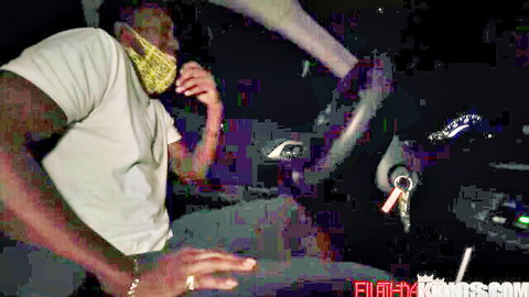 Tattooed black guy in yellow mask drives car with white babe's sexy leg teasing his lap