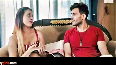 Sexy Indian woman in low-cut top flashes cleavage while flirting intensely with handsome guy on couch