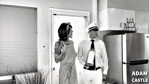 Vintage housewife in apron flirts with pilot captain holding milk bottle in retro kitchen