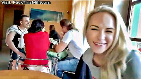 Smiling Czech blonde MILF in casual gray top and jeans at cafe table with group