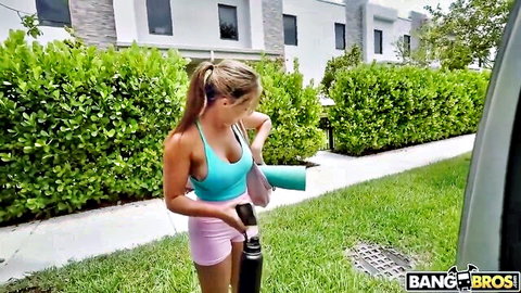 Monica Minx in teal sports bra and pink shorts stretching before yoga with Rocket Powers