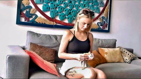 Amateur blonde beauty in tank top and shorts, teasing on couch