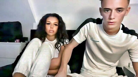 Brunette teen in white top and grey joggers spreads legs teasing next to boyfriend on webcam