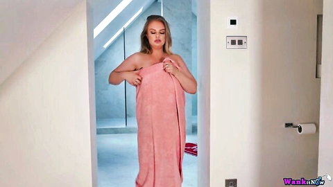 Sexy blonde babe clutching pink towel over her tits and pussy in steamy bathroom doorway