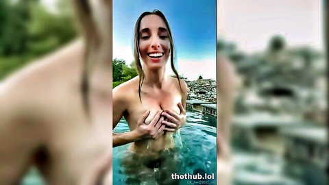 Christina Khalil naked in pool, smiling topless with hands covering breasts