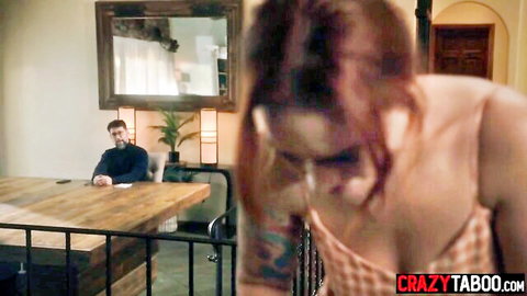 Redhead MILF bends over table showing big ass and cleavage in tight dress while bearded man watches hungrily