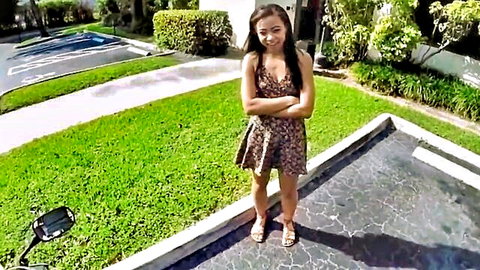 Cute Asian teen in short leopard dress posing with arms crossed outdoors in public parking lot