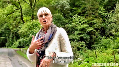 Blonde Czech tour guide looking apologetic in forest jacket and scarf