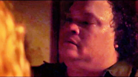 Close-up of intense chubby man with curly hair and earrings staring fiercely