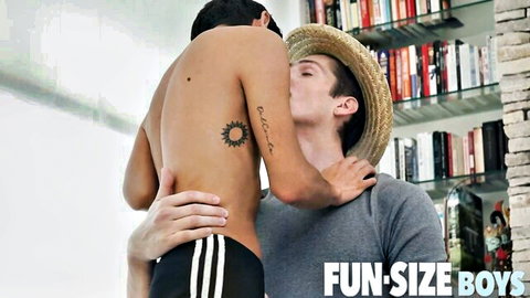Intimate gay couple embrace, shirtless twink kissed on neck by hatted partner