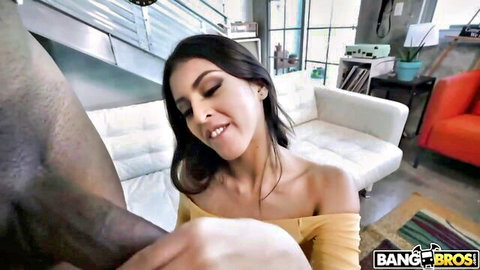 Smiling brunette in off-shoulder yellow top embraced by black man in interracial tease