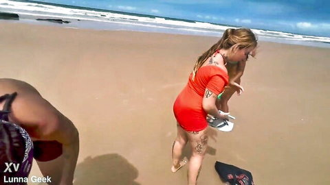 Blonde in red dress and brunette in bikini on sunny beach outdoor passion