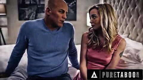 Bald black man in blue sweater with busty blonde in pink dress on bed
