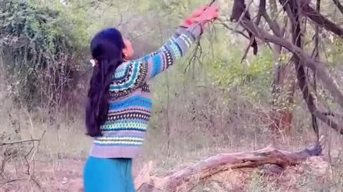 Priya in colorful sweater reaching up, big ass in tight blue leggings outdoors