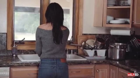 Asian MILF in tight jeans and off-shoulder sweater at kitchen sink