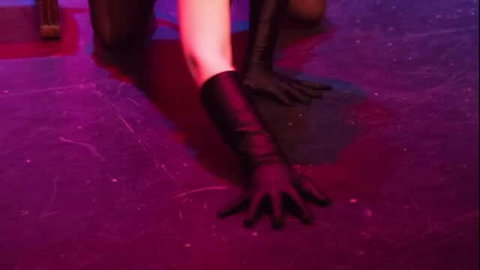 Closeup of pale woman's gloved hand on purple-lit stage in erotic werewolf book reading