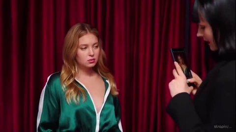 Curvy blonde in deep V green satin tracksuit teased by woman on theater stage