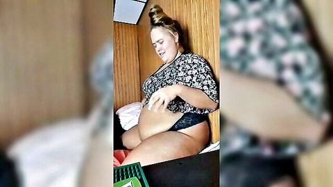 Chubby woman lifts floral top exposing huge fat belly and black lace thong panties on bed
