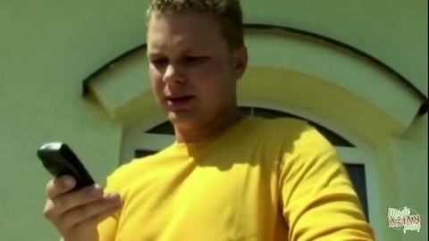 Man in yellow shirt checking phone outdoors