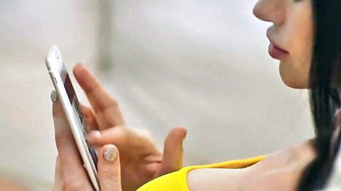 Brunette woman in yellow top holding phone, teasing vacation gape vibe