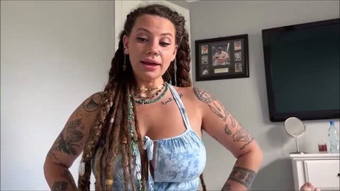 Indica Flower in blue tie-dye top with tattoos and dreadlocks