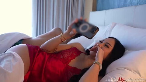 Vivienne Vo in red lingerie holding phone answering a call on bed