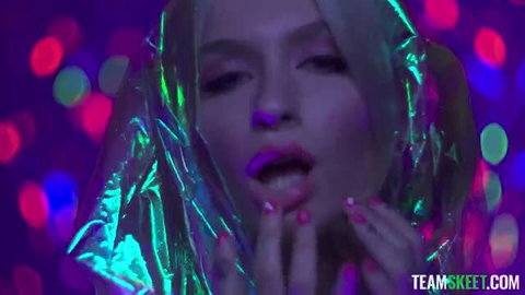Emma Rosie in shiny plastic wrap with neon makeup, close-up face and hands