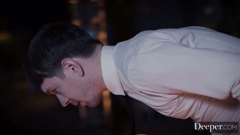 Man in white dress shirt bent over in dimly lit room