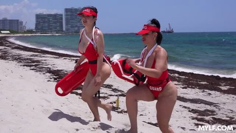 Miki Moon and Miss Raquel in red lifeguard swimsuits on the beach
