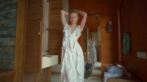 Vika Kucherenko posing in sheer white ruffled dress with arms raised