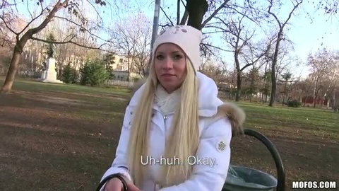 Kiara Lord in white winter coat and hat, public park outdoor scene