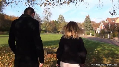 Couple walking in park, blonde woman with man in black coat, autumn outdoor scene