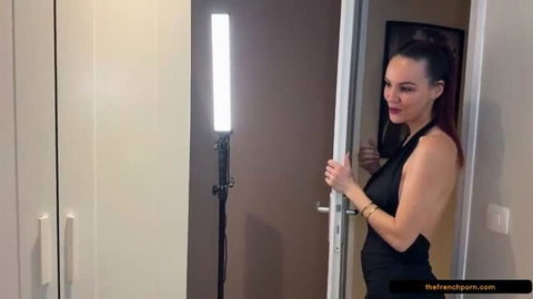 Cataleya in black dress posing by door with professional lighting setup
