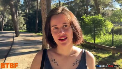 Ruby in park setting, short brown hair, chest tattoos, outdoor scene