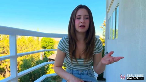 Alana Rose in striped top and jeans on balcony, talking to camera