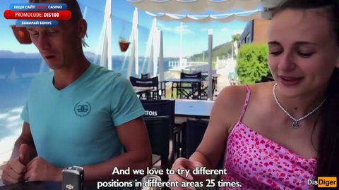 Katty West in pink dress at outdoor table with male partner