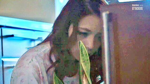 Mako Oda in pink top, peering at tentacle-like plant leaf in JAV scene