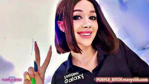 Purple Bitch smiles playfully in black Samsung shirt with colorful nails, peace sign pose